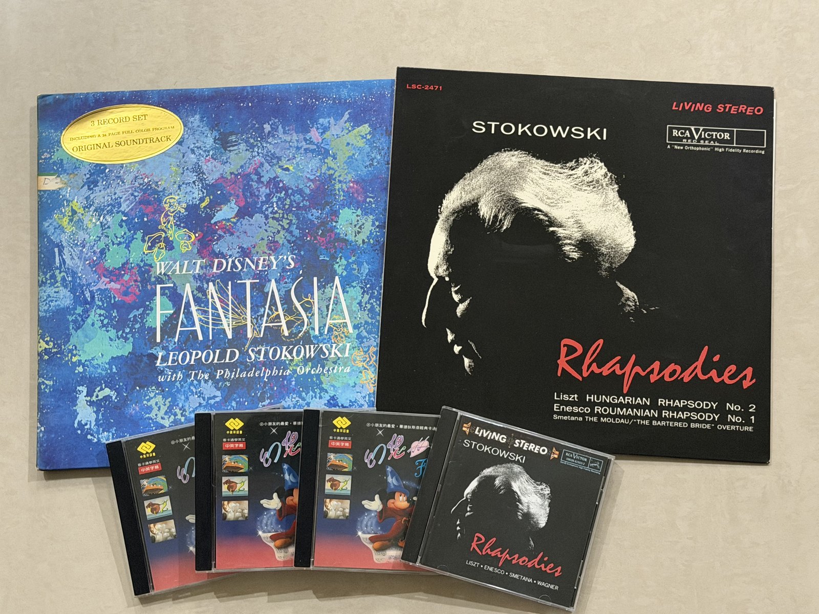 右邊那張黑底紅字的就是《狂想曲集》，封面是 Stokowski 的側臉——追著唱片聖經買回來的第一張古典黑膠，跟了我三十年。前排右邊那張是後來的 CD，封面多印了一個 WAGNER：黑膠上沒有那兩首，這篇談的是黑膠上的四首。